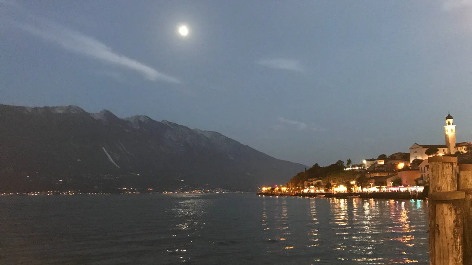 Abendstimmung am Gardasee mit beleuchtetem Ufer und Vollmond über den Bergen