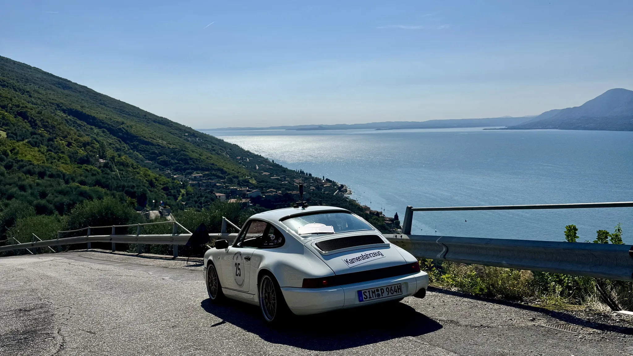 Weißer Porsche 911 Carrera 2 an einer Passstraße hoch über dem Gardasee