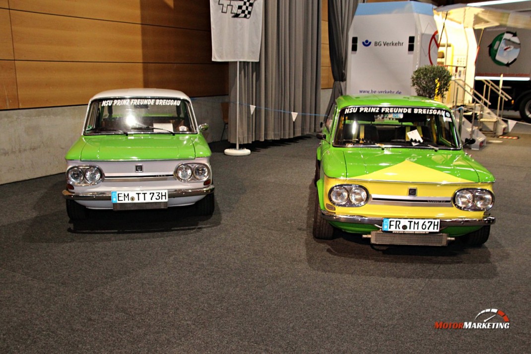 Zwei grüne Oldtimer-Limousinen nebeneinander in einer Messehalle zur Automobil Freiburg 2016, mit Bannern und Ausstellungsstand im Hintergrund