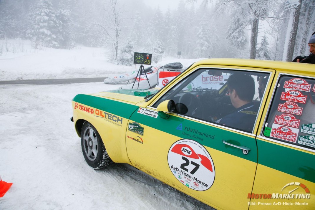 Gelb-grüner Youngtimer mit Startnummer bei Schneefall während der AvD-Histo-Monte Rallyetour im verschneiten Wald