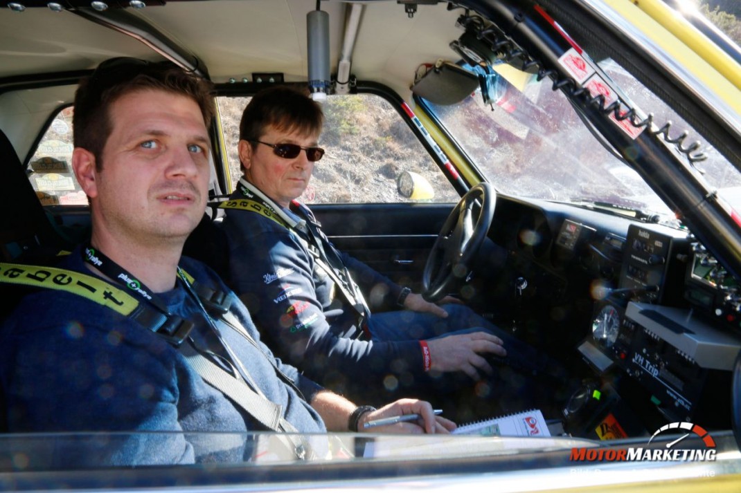 Zwei Teilnehmer in einem Oldtimer-Rallye-Fahrzeug bei der AvD-Histo-Monte, Fahrer konzentriert am Steuer, Beifahrer mit Navigationsunterlagen