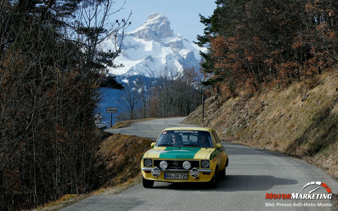 Gelber Oldtimer-Rallye-Wagen auf bergiger Gebirgsstraße mit schneebedecktem Gipfel im Hintergrund bei der AvD-Histo-Monte