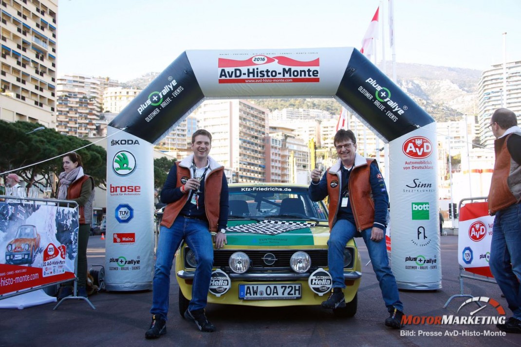 Zwei Teilnehmer mit Youngtimer-Rallye-Fahrzeug unter dem Zielportal der AvD-Histo-Monte 2016 in urbaner Bergkulisse