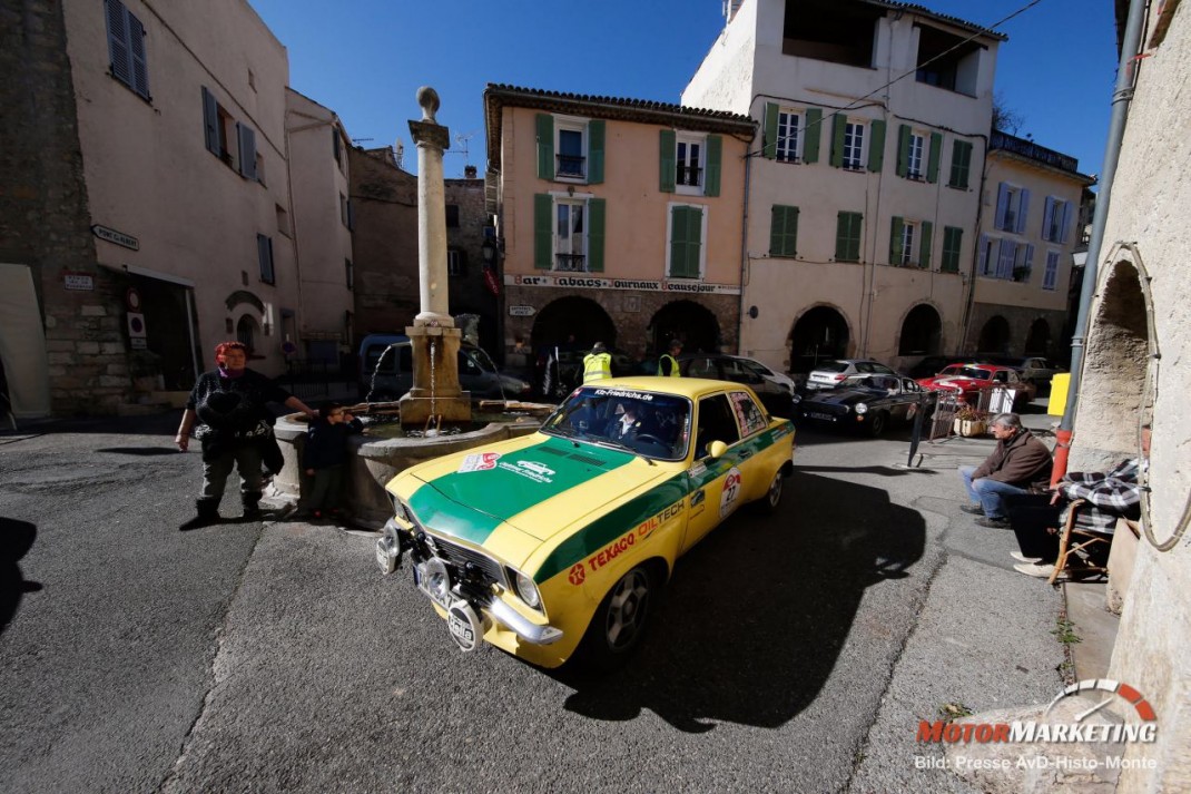 Gelber Oldtimer-Taxi mit grünem Dach auf italienischem Dorfplatz bei der AvD-Histo-Monte 2016, weitere Klassiker und Zuschauer im Hintergrund