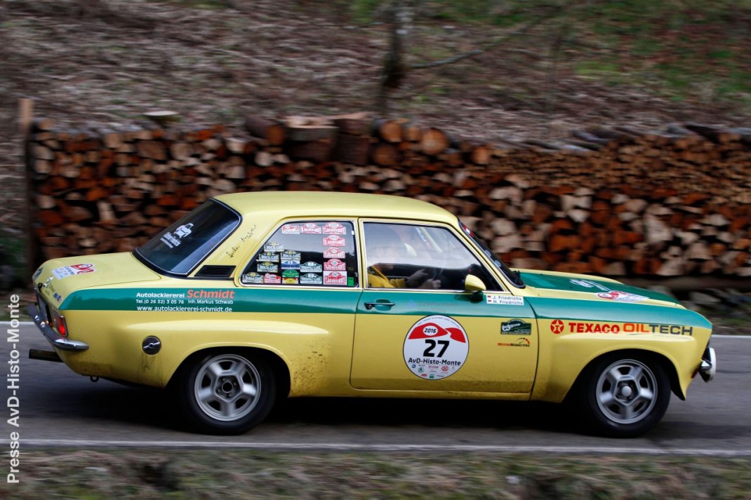 Gelber Opel Ascona mit grünem Streifen und Oldtimer-Rallyenummern bei der AvD-Histo-Monte, vollgepackt mit Ausrüstung auf kurviger Straße