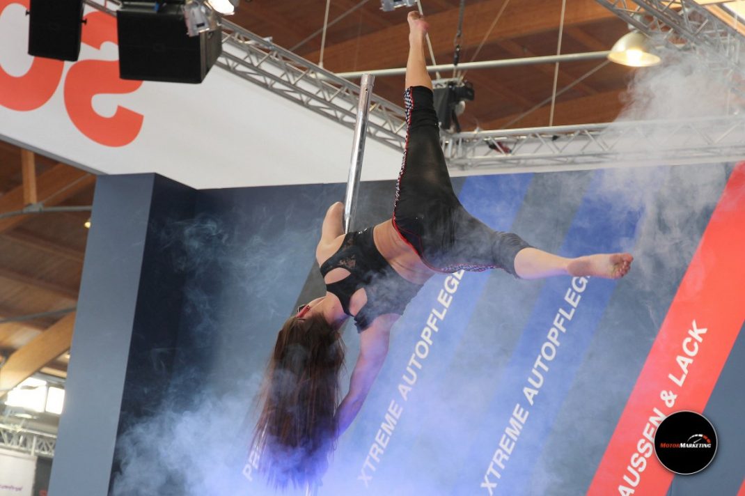 Performerin in schwarzem Outfit bei Luftakrobatik-Show auf der TuningWorld Bodensee mit Tragebühne und Bühnenlicht