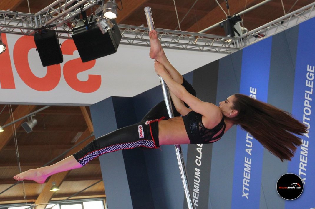 Performerin beim Pole-Dance auf der TuningWorld Bodensee 2016 in einer Eventhalle mit Banner im Hintergrund
