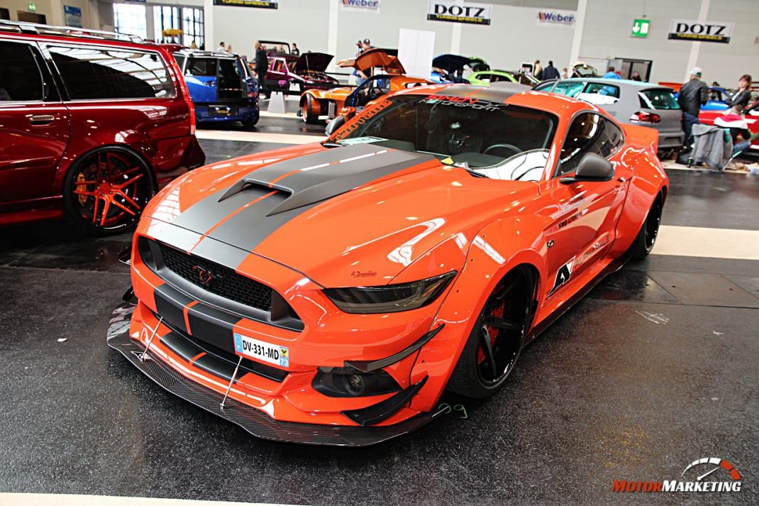Orangeroter Mustang-Sportwagen mit grauen Streifen auf Messe-Hallenboden beim European Tuning Showdown