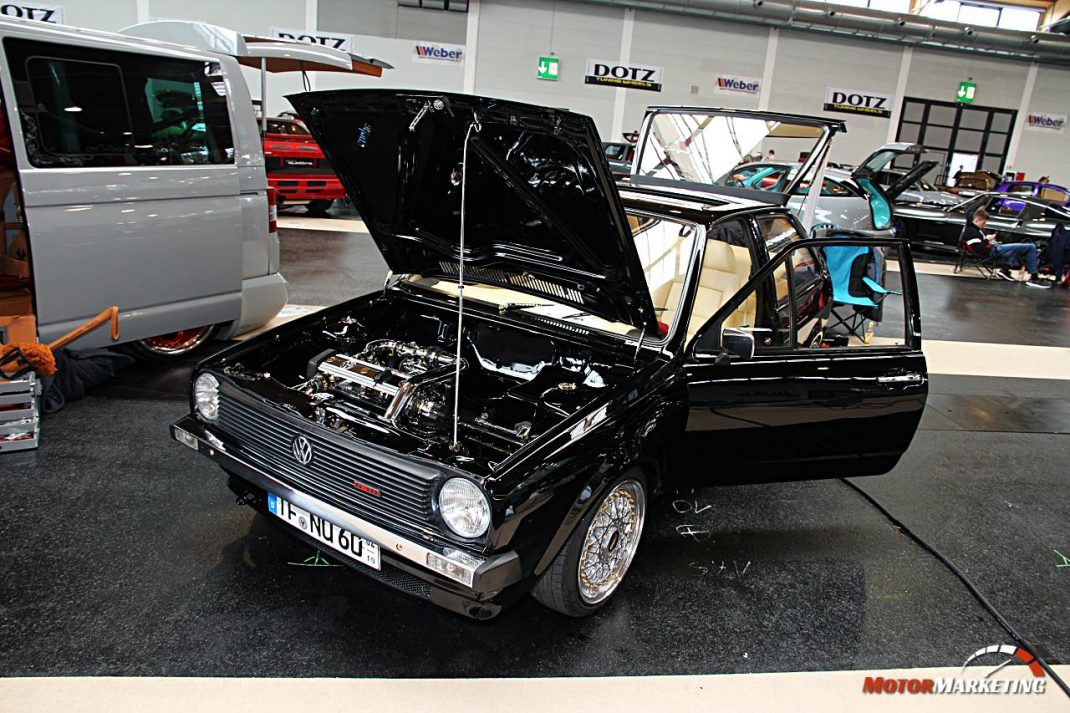 Schwarzer VW Golf mit geöffneter Motorhaube und aufgeschlagenen Türen in Messehalle beim European Tuning Showdown