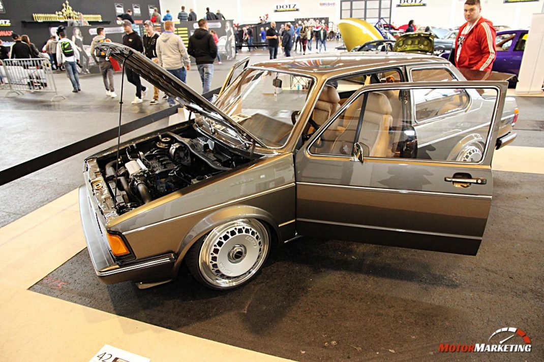 Goldfarbener Youngtimer mit geöffneter Motorhaube und Tür auf Ausstellungsfläche des European Tuning Showdown