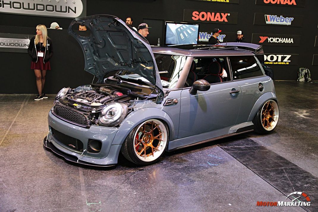 Silberner Youngtimer-Kompaktwagen mit geöffneter Motorhaube und goldenen Felgen auf Event-Bühne mit Sponsorenlogos