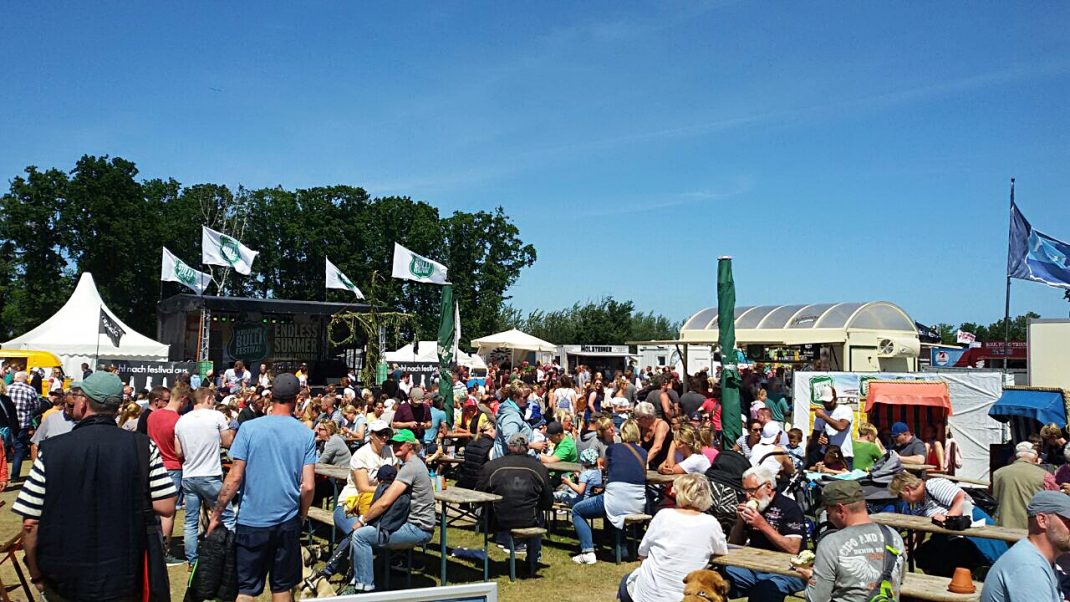 Große Zeltstadt mit Bühne und hunderten Besuchern beim Midsummer Bulli Festival auf Fehmarn