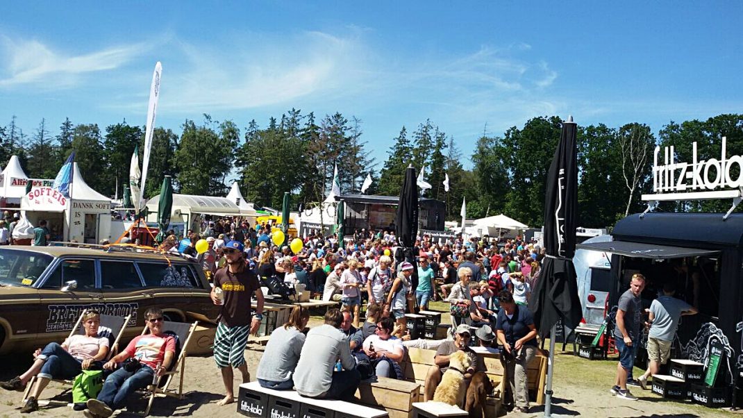 Oldtimer-Busse und Besucher auf großem Festivalgelände mit Bühnen, Ständen und Zuschauern beim Midsummer Bulli Festival