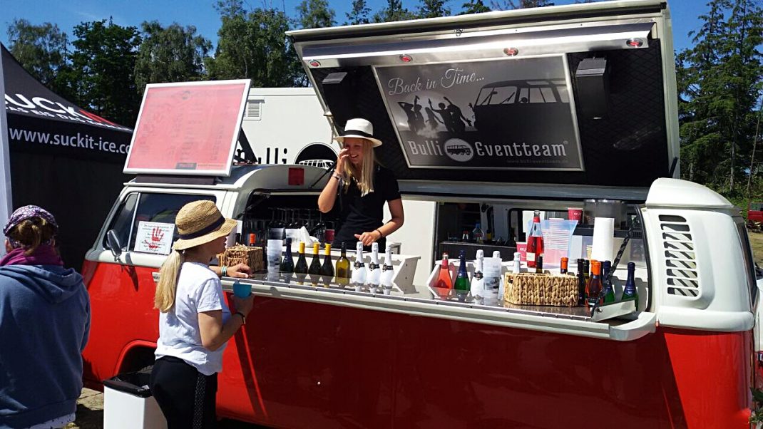 Verkaufsstand an einem rot-weißen Bulli-Foodtruck beim Midsummer Bulli Festival auf Fehmarn mit Getränken und Snacks