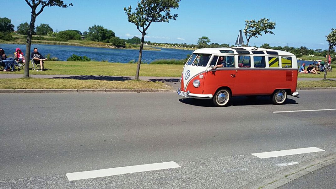 Roter und weißer VW Bulli fährt auf der Straße beim Midsummer Bulli Festival auf Fehmarn