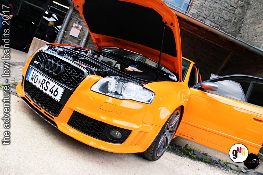 Orangefarbener Youngtimer-Sportwagen mit geöffneter Motorhaube bei Tuning-Veranstaltung im Steinbruch