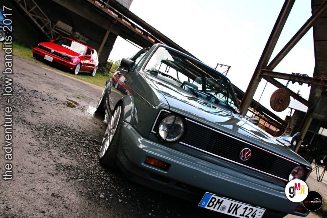 Volkswagen Golf GTI und roter Oldtimer-Sportwagen unter Industriebrücke bei Tuning-Treffen Low Bandits 2017