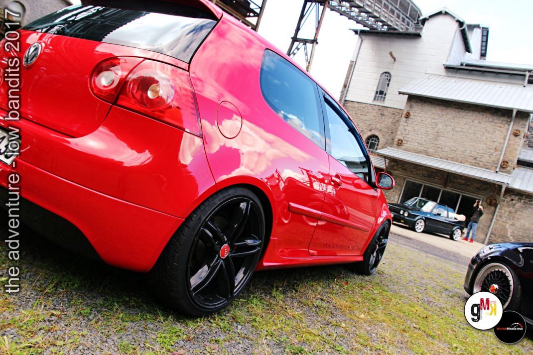 Roter Youngtimer-Kleinwagen mit Custom-Felgen auf dem Veranstaltungsgelände des Tuning-Events