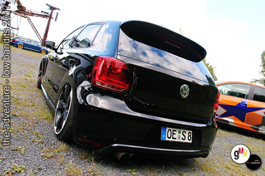 Schwarzer Youngtimer-Kompaktwagen mit roten Rückleuchten auf Tuning-Event im Steinbruch mit weiteren Fahrzeugen
