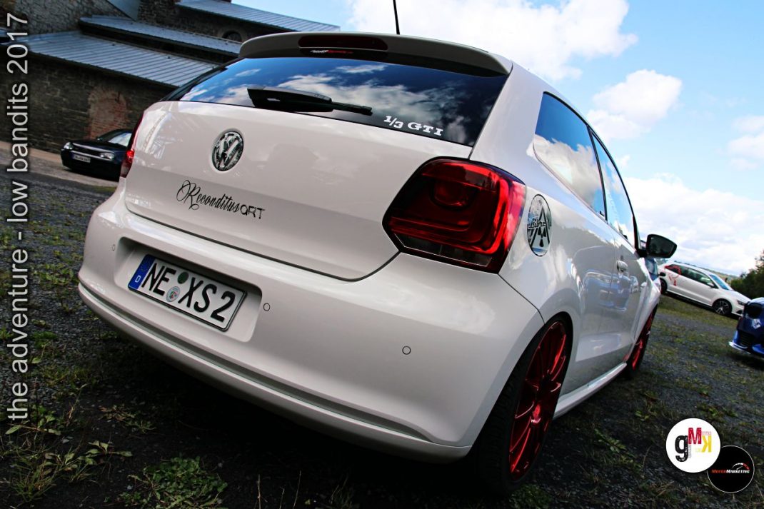 Weißer Youngtimer-Sportwagen mit rotem Felgen-Set von hinten auf einem Veranstaltungsgelände
