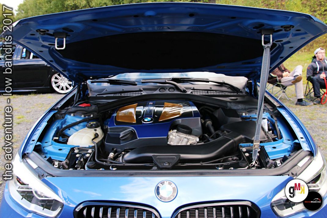 Geöffnete Motorhaube eines blauen BMW-Youngtimers mit verchrömtem Motorblock bei Tuning-Treffen