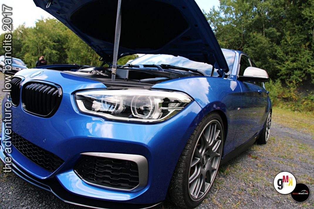 Blauer Youngtimer-Sportwagen mit geöffneter Motorhaube bei Tuning-Treffen im Grünen