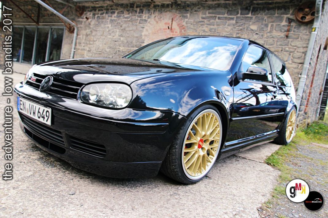 Schwarzer VW Golf mit goldenen Felgen vor Steinbruch-Kulisse, getunt und tiefergelegt bei Tuning-Event