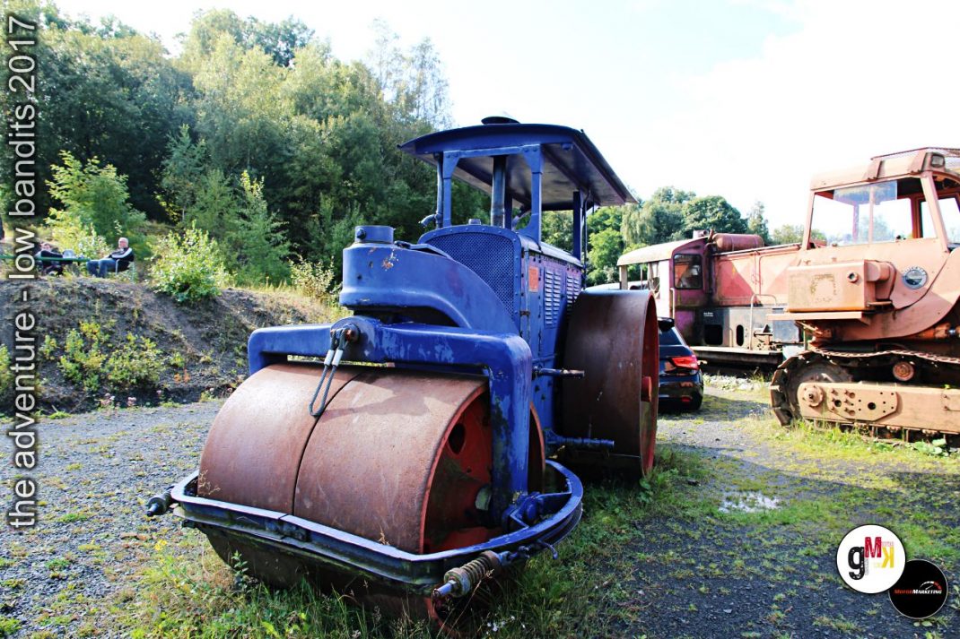 Blauer Walzenzug und rostiger Raupenbagger in Steinbruchgelände während der Veranstaltung
