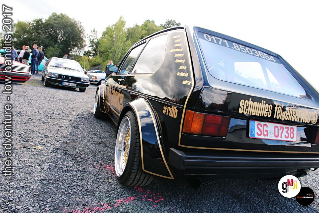 Schwarzer Youngtimer mit Golddekor und Beschriftung beim Tuning-Event im Steinbruch, dahinter weitere Fahrzeuge und Zuschauer