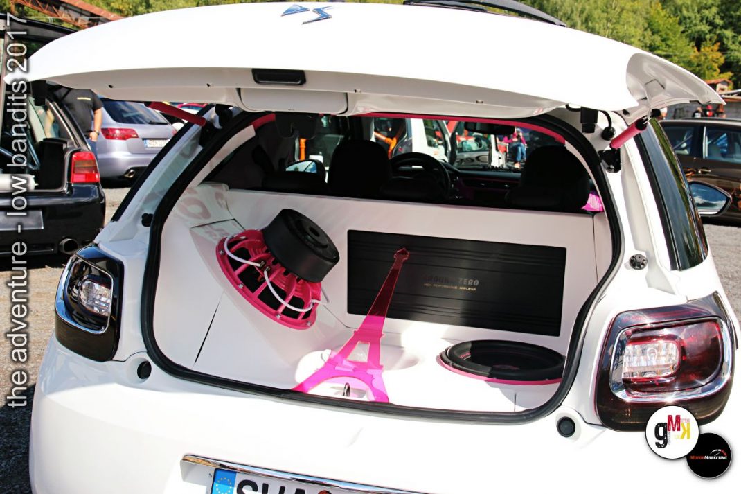 Weißer Youngtimer mit offener Heckklappe zeigt pink-schwarze Tuning-Ausstattung beim Treffen The adventure low bandits
