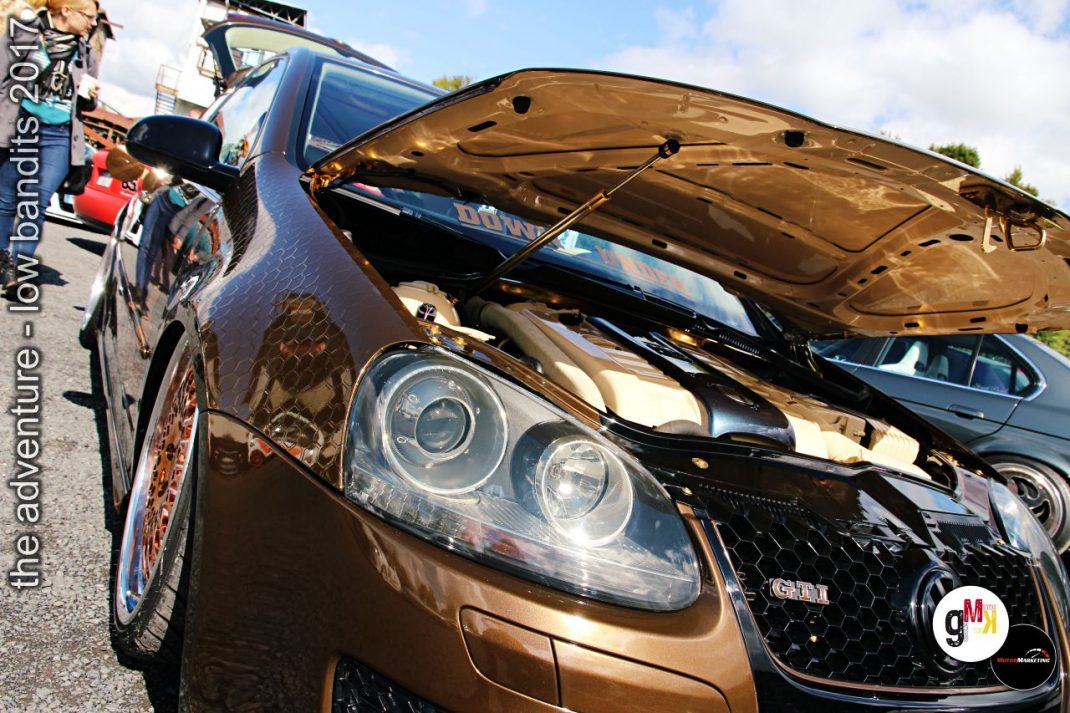 Schwarzer Youngtimer mit offener Motorhaube auf Tuning-Treffen, Fahrer präsentiert sein Fahrzeug