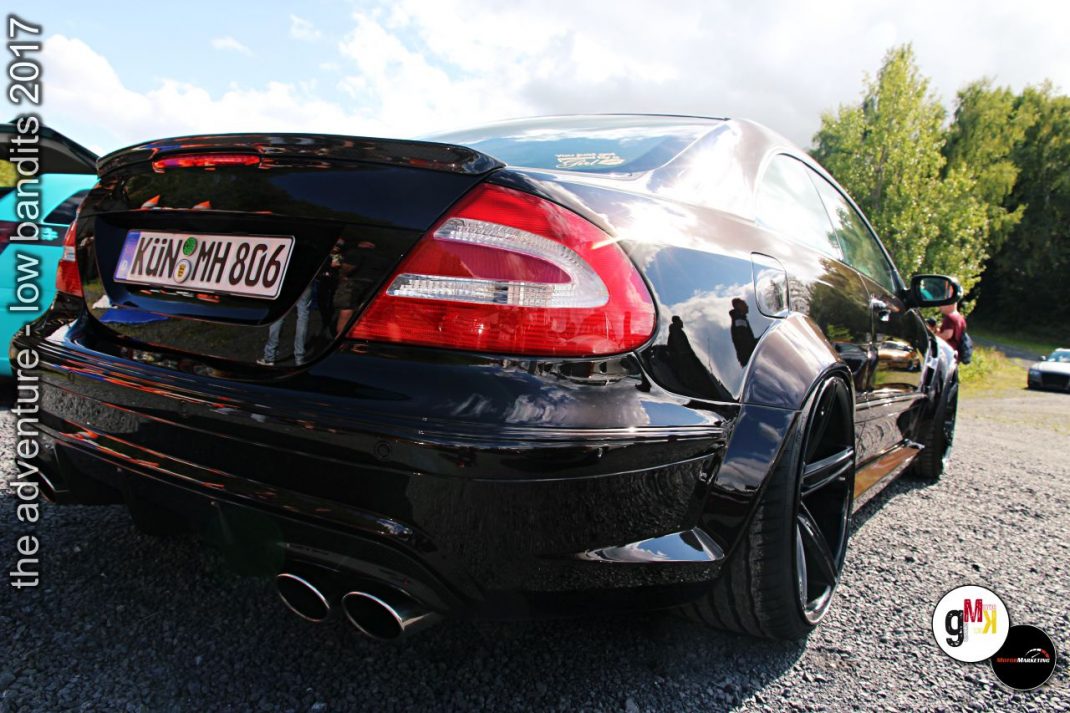 Schwarzer Youngtimer-Sportwagen mit Heckspoiler und roten Rückleuchten beim Tuning-Event