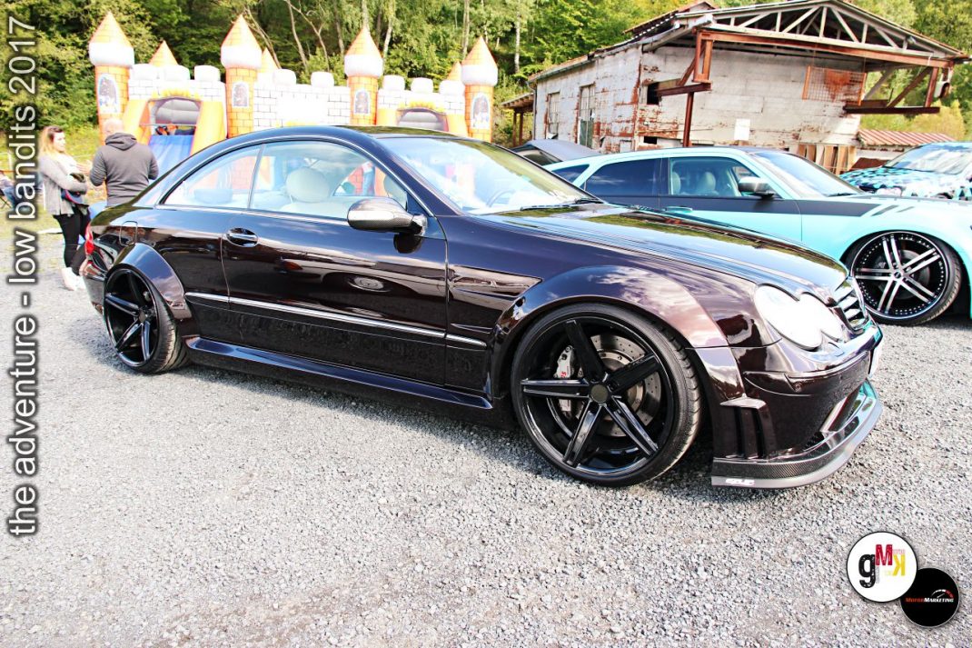 Schwarze Youngtimer-Limousine mit tiefergelegtem Fahrwerk und Tuning-Rädern auf Treffen im Steinbruch