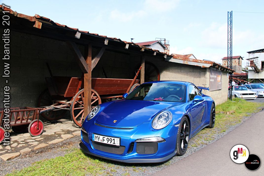 Blauer Porsche 911 GT3 RS neben historischem Holzwagen bei Youngtimer-Event im Steinbruch