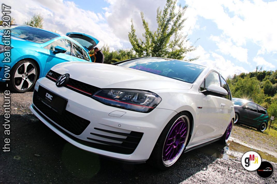 Weiße Youngtimer-Limousine mit Spoiler und violetten Rädern neben blauem Cabrio auf Treffen der Low Bandits 2017