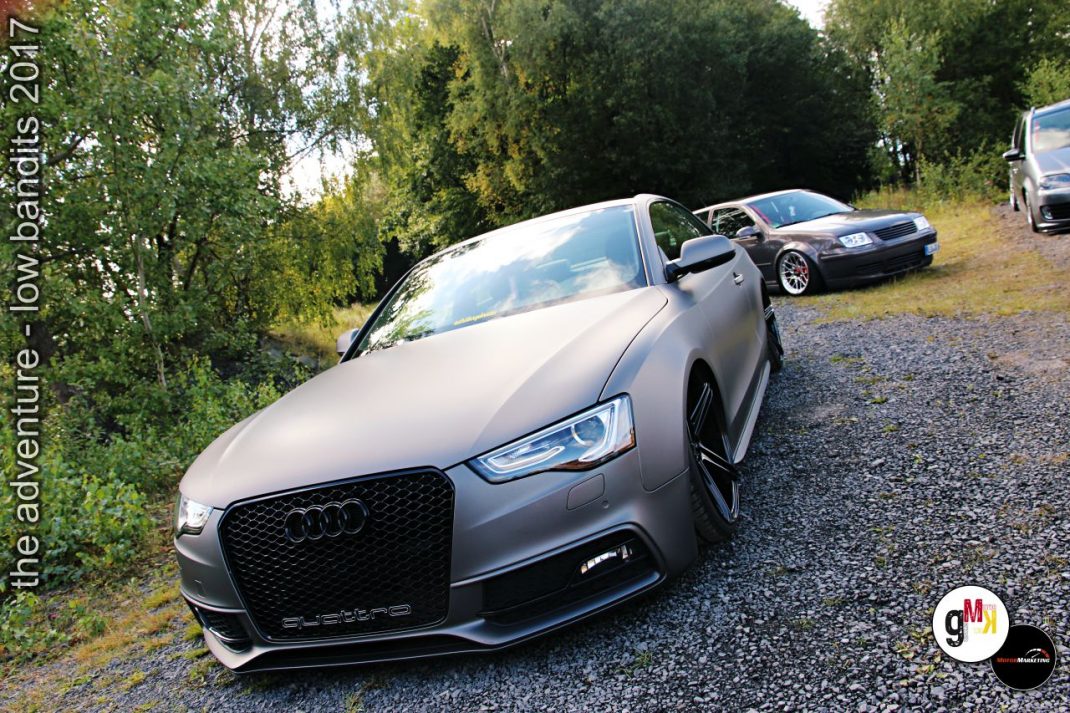 Audi RS5 Cabrio und weitere Sportwagen auf Kiesplatz vor Birkenwald bei Tuning-Treffen
