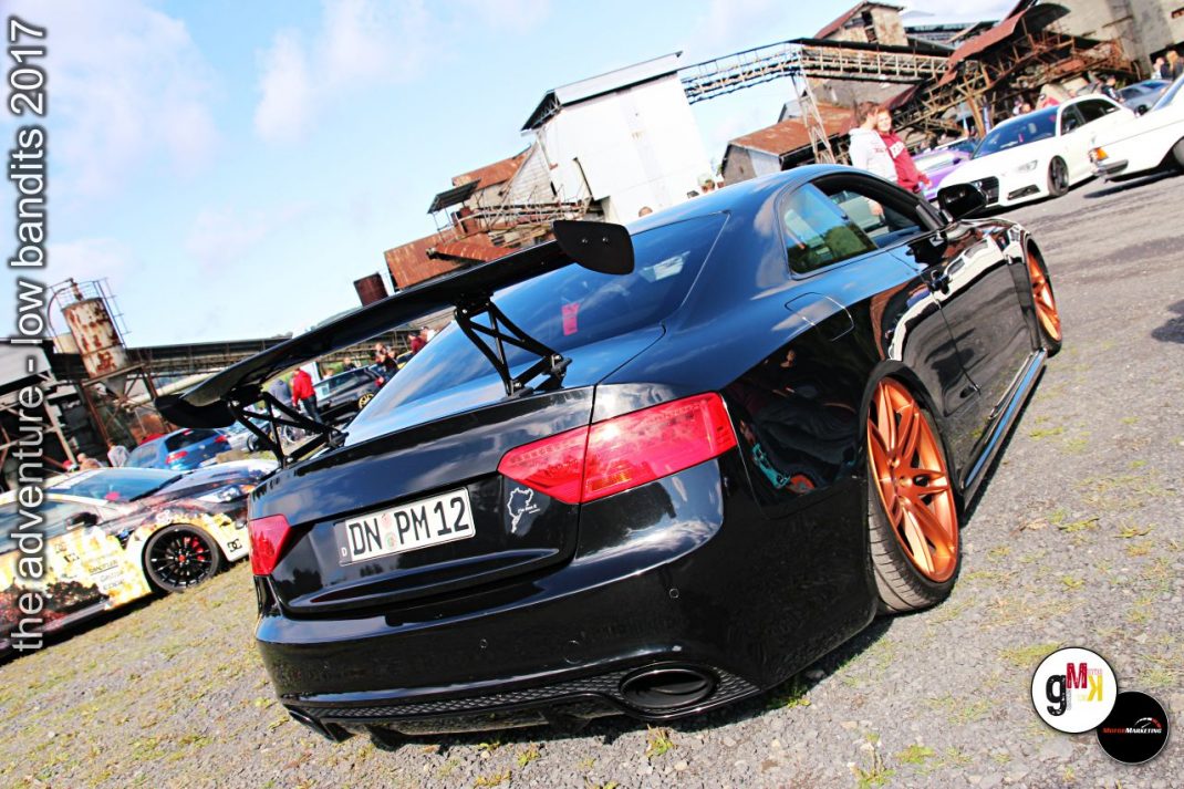 Blauer Sportwagen mit Sportlenkrad und orangefarbenen Felgen auf Tuning-Treffen im Steinbruch