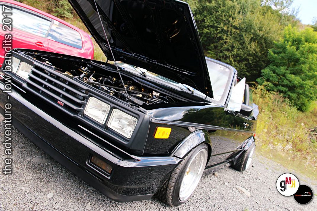 Schwarzer Oldtimer-Limousine mit geöffneter Motorhaube und rosa Youngtimer im Hintergrund beim Tuning-Treffen im Steinbruch
