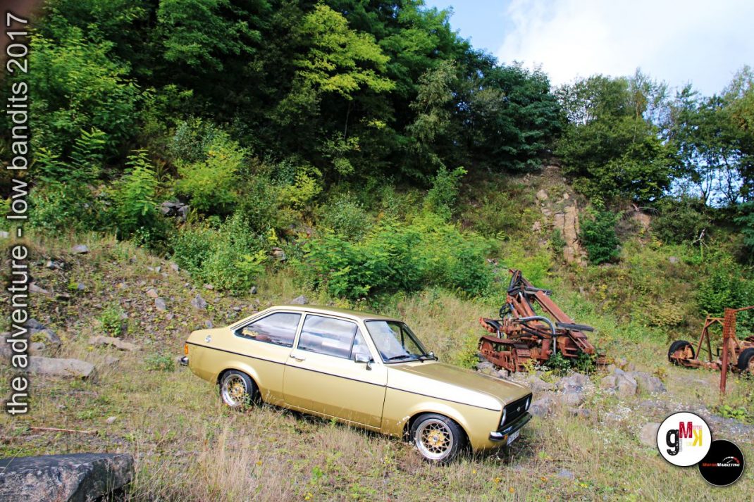 Goldener Oldtimer-Kompaktwagen in Steinbruch-Kulisse mit Vintage-Maschinen und bewachsenem Hang