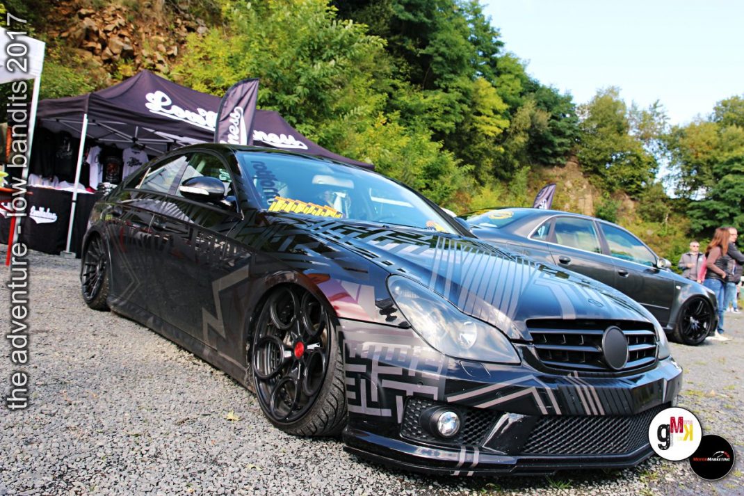 Schwarz lackierter Youngtimer-Sportwagen mit Tuning-Aerodynamik und breiten Felgen bei Tuning-Event im Steinbruch