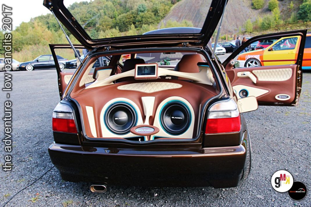 Youngtimer mit aufgeklapptem Kofferraum zeigt individualisierte Innenausstattung mit braunem Leder und großen Subwoofern beim Tuning-Event im Steinbruch