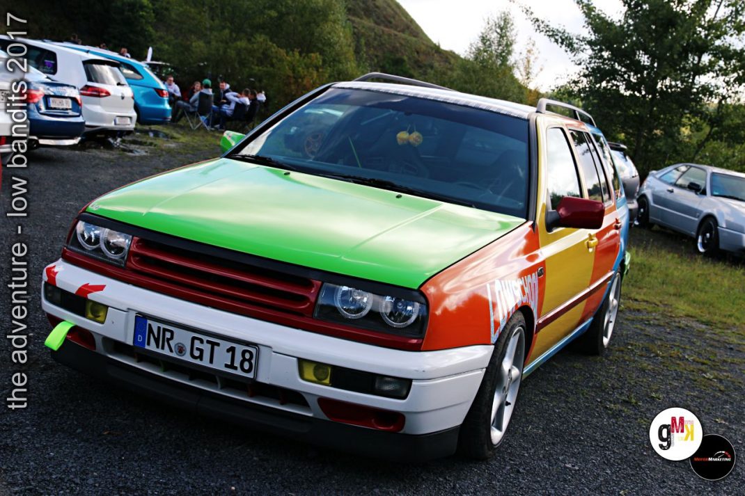 Youngtimer-SUV mit mehrfarbiger Lackierung in Grün, Orange und Rot beim Tuning-Treffen im Steinbruch, weitere Fahrzeuge im Hintergrund