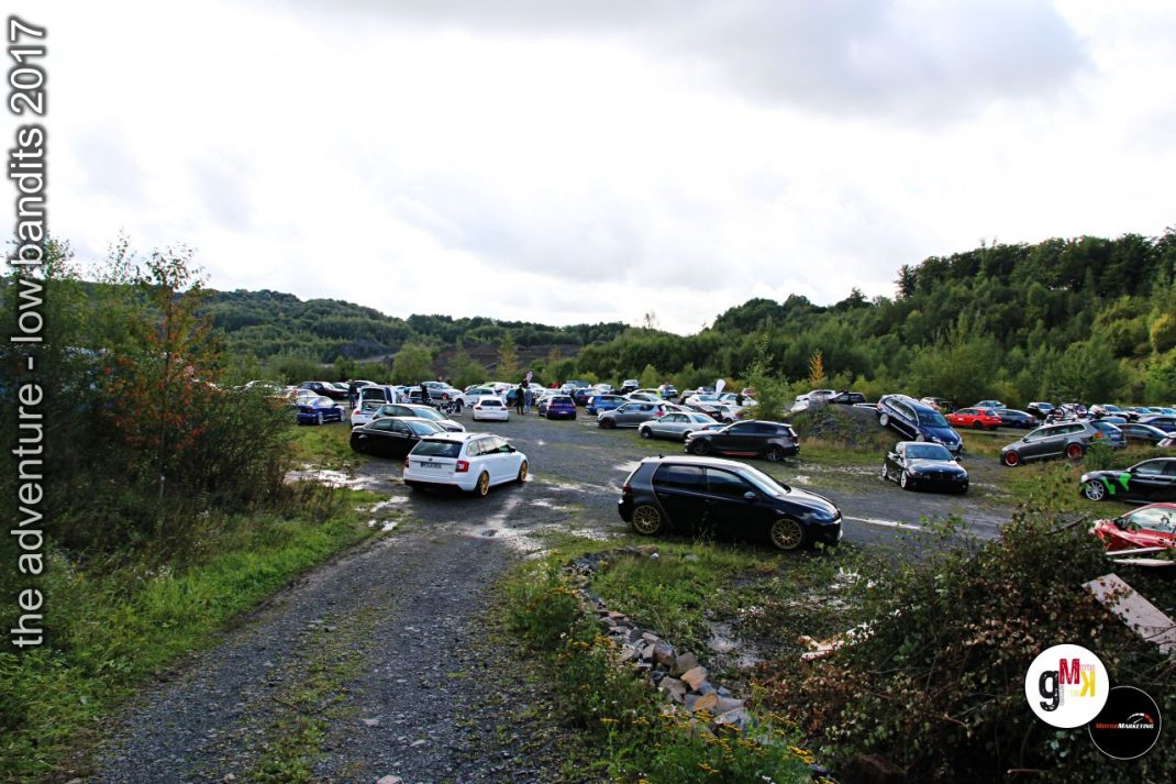 Parkplatz mit zahlreichen getunten Fahrzeugen in bewaldeter Landschaft beim Low Bandits Tuning-Event 2017
