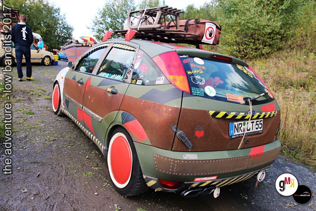 Braun-rot lackierter Youngtimer mit Kunstflugzeug-Dachgepäck und bunten Aufklebern bei The Adventure Low Bandits 2017