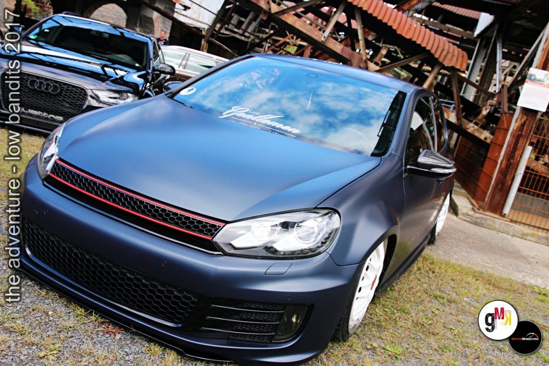 Dunkelblauer VW Golf mit rotem Grill auf Tuning-Treffen im Steinbruch, weitere Youngtimer im Hintergrund