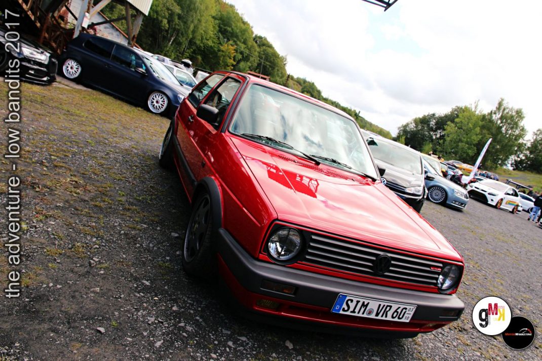 Roter Oldtimer-Cabrio mit offener Tür auf Parkplatz mit weiteren Fahrzeugen bei Tuning-Treffen