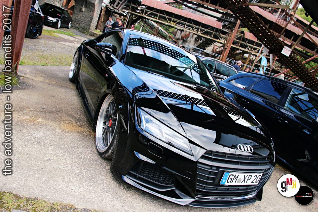 Schwarzer Youngtimer mit geöffneter Fahrertür und verchromten Details auf dem Parkplatz einer Tuning-Veranstaltung im Steinbruch