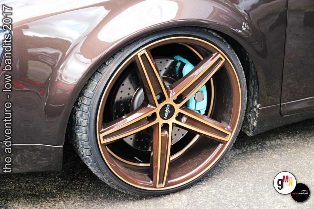 Ausschnitt eines Youngtimer-Fahrzeugs mit kupferfarbener Felge und Bremsenanlage beim Tuning-Event