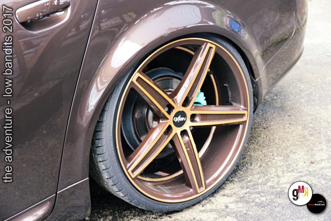 Detailaufnahme eines Youngtimers mit goldfarbener Leichtmetallfelge und tiefergelegtem Fahrwerk beim Tuning-Event