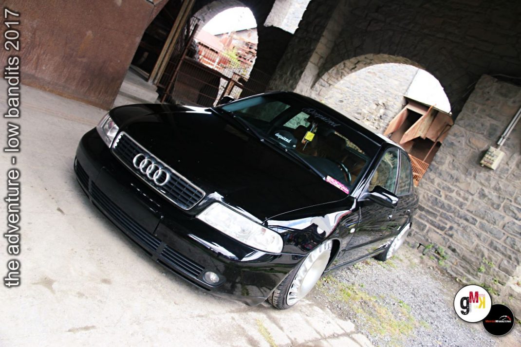 Schwarze Audi-Limousine mit tiefergelegtem Fahrwerk in Industrielocation während Tuning-Treffen 2017